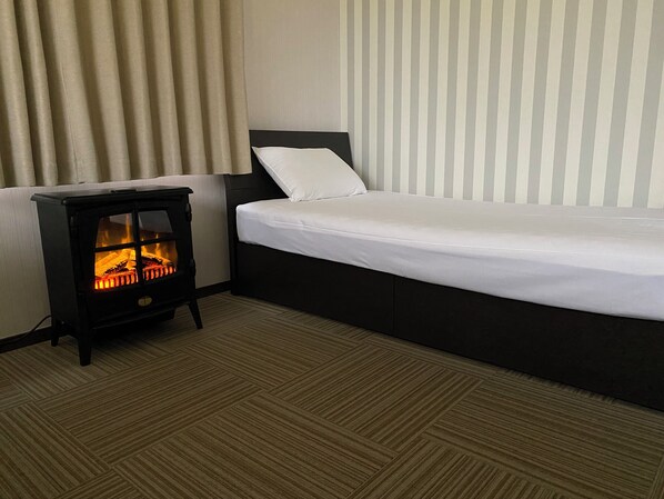 A hotel room with a bed, a small black heater, and a striped wall.
