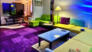 A modern living room with a TV, green and yellow sofas, a coffee table, and a purple carpet.