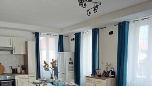 A modern kitchen with white cabinets, a dining area with a table set for four, and a red leather sofa in the living area. - Bright apartment in Mertzwiller (Mertzwiller)