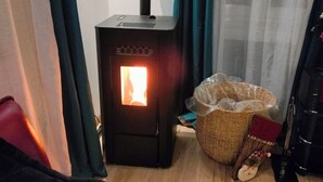A room with a wood-burning stove, a wicker basket, and a red chair. - Bright apartment in Mertzwiller (Mertzwiller)