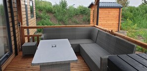 A covered outdoor seating area with wicker furniture and a glass table.