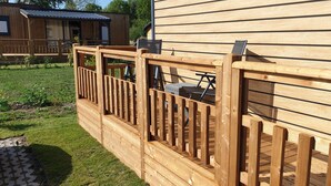 A wooden deck with a railing, a small table, and a chair. - Sfeervol chalet in Renesse met airco 3 slpk 2 badk (Renesse)