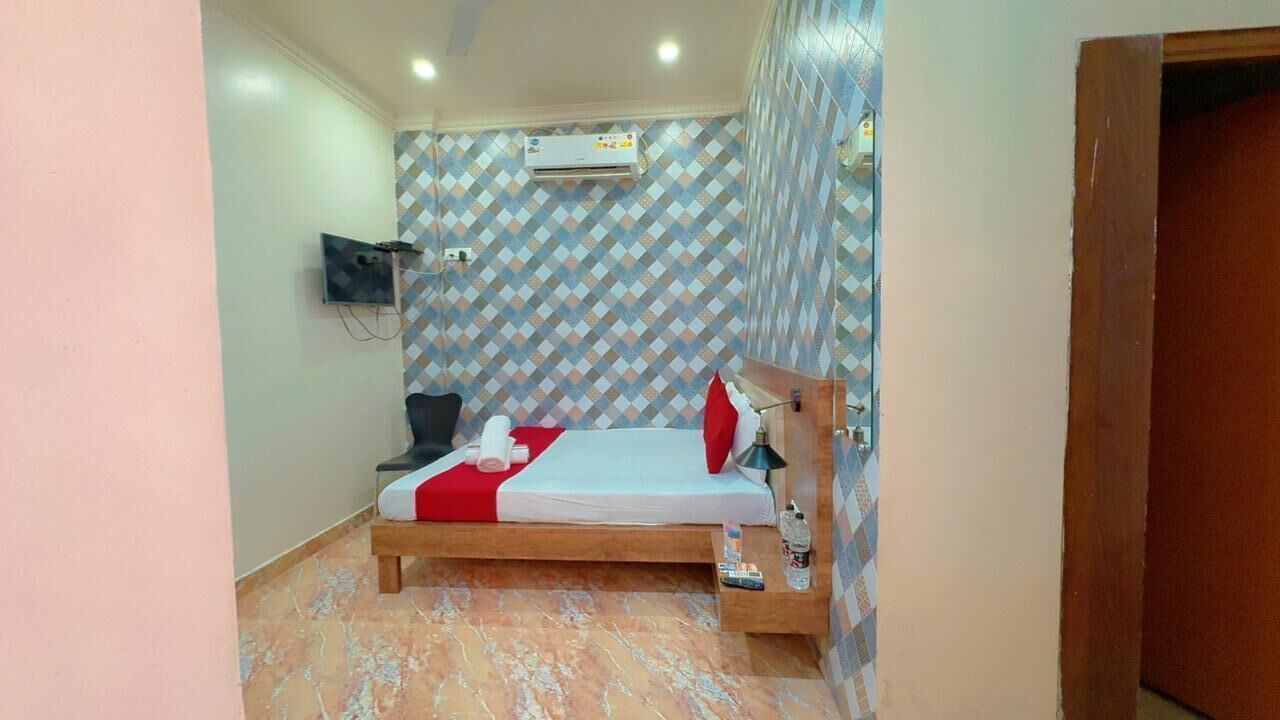 A bedroom with a bed, a TV mounted on the wall, and an air conditioning unit.