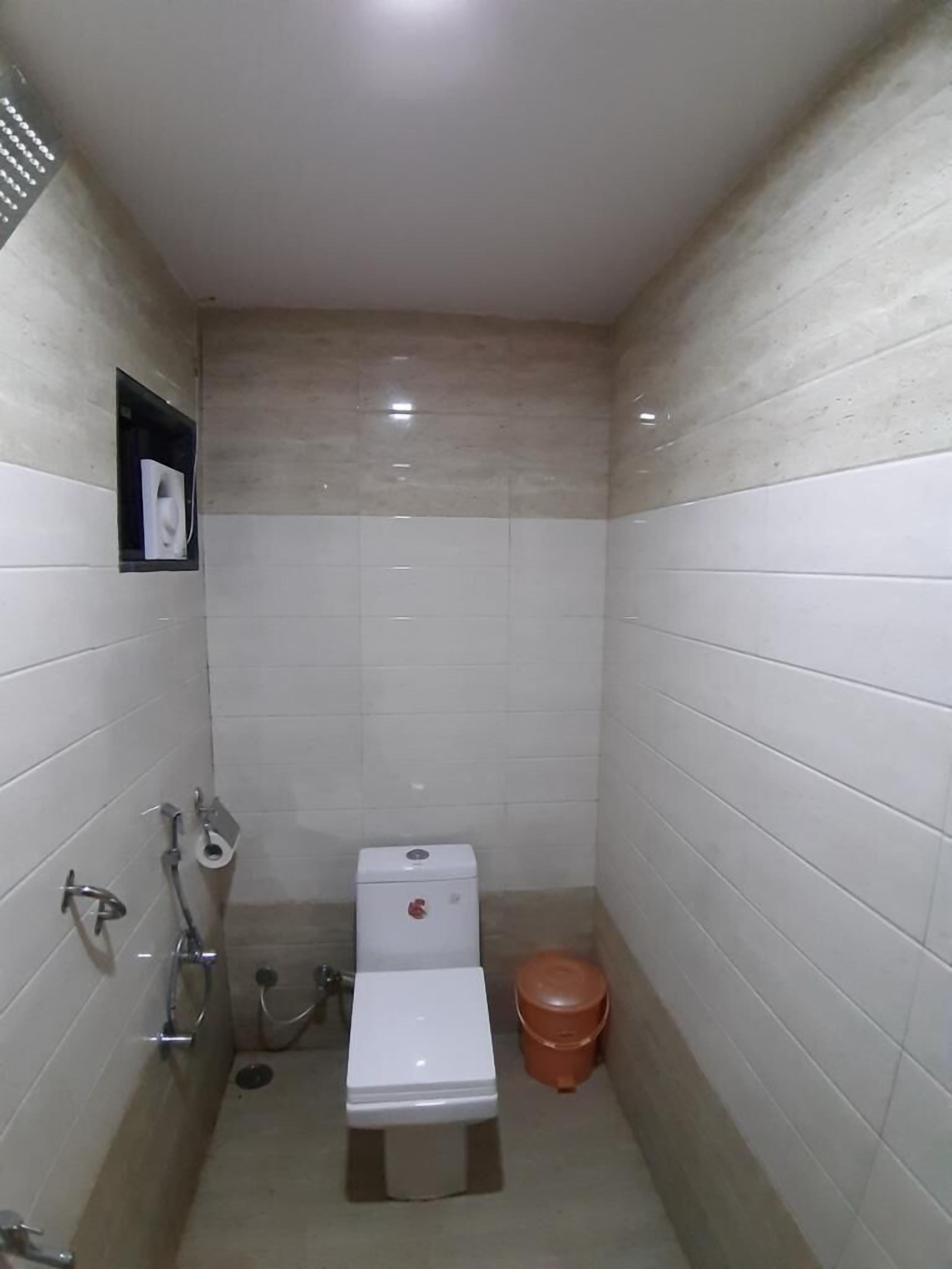 A small, tiled bathroom with a toilet, bidet, and a trash bin.