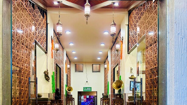 A hotel lobby with a patterned floor, wooden reception desks, and decorative wall panels.