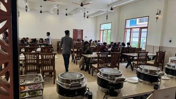A cafeteria with multiple tables and chairs, buffet stations, and ceiling fans.
