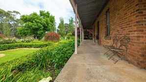 A covered outdoor area with a brick building, a concrete pathway, and metal chairs. - Cosy north facing priv selfcontained Suite set within large garden, 7min to town (Hamilton)