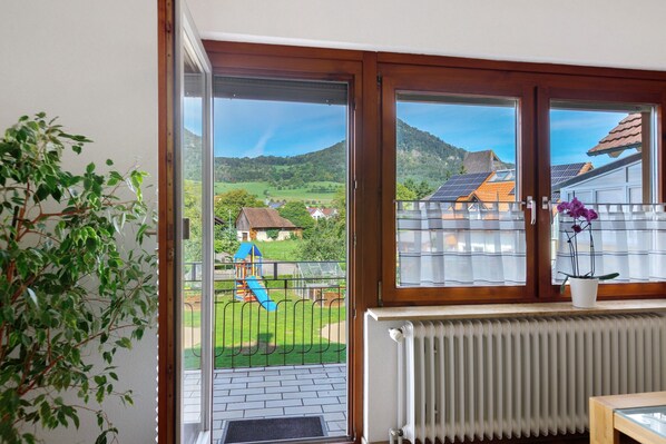 A room with a view of a playground, a radiator, and a potted plant.