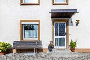 A building with a bench outside, a door with a glass panel, and two potted plants. - Holiday Apartment 'Hewenpanorama 4' with Mountain View, Shared Terrace and Wi-Fi (Engen)