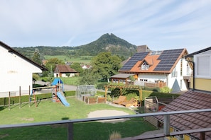 Een woonwijk met een speeltuin, zonnepanelen op een huis en een berg op de achtergrond.