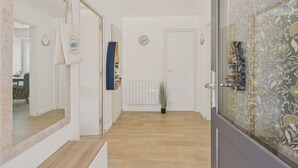 Ein Flur mit Holzboden, einem Spiegel, einer Uhr und einer Tür mit floralem Muster.