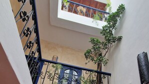 Un intérieur à plusieurs niveaux, avec un escalier, un coin repas et une vue sur l’extérieur.