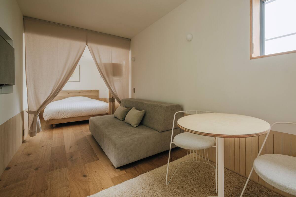 Een slaapkamer met een bed, een bank, een ronde tafel en een raam.