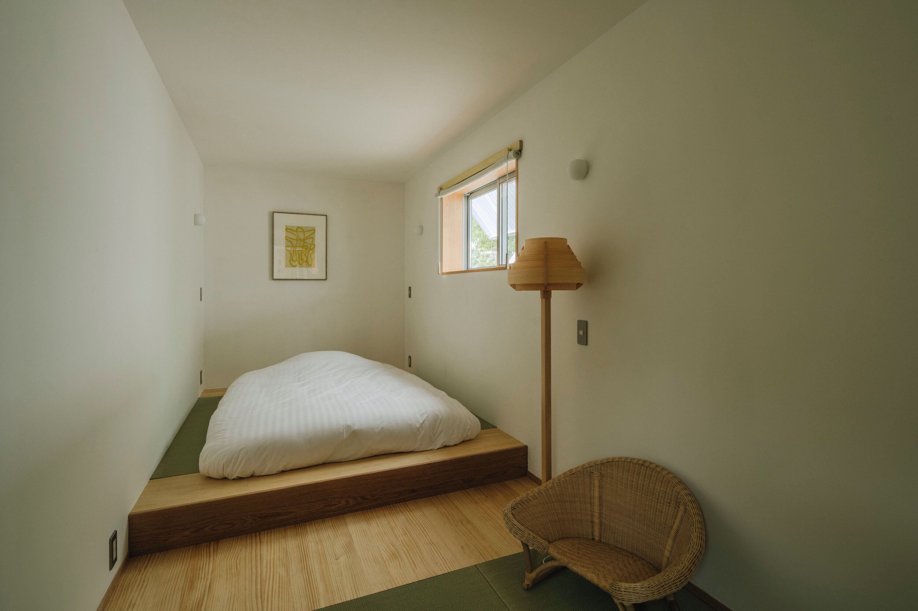 Una habitación minimalista con una cama individual, una lámpara de pie y una silla.