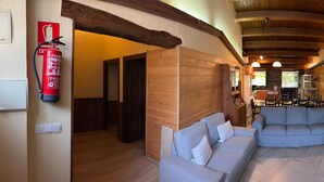 A cozy interior with a wooden ceiling, a fireplace, a sofa, and a dining area. - Beautiful and cozy rural house in El Bierzo (Ocero)