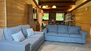 A cozy living room with a grey sofa and a blue sofa, wooden walls, and a herringbone floor pattern. - Beautiful and cozy rural house in El Bierzo (Ocero)