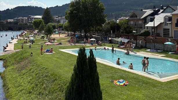A swimming pool area with people, a grassy area, and buildings in the background. - Beautiful and cozy rural house in El Bierzo (Ocero)
