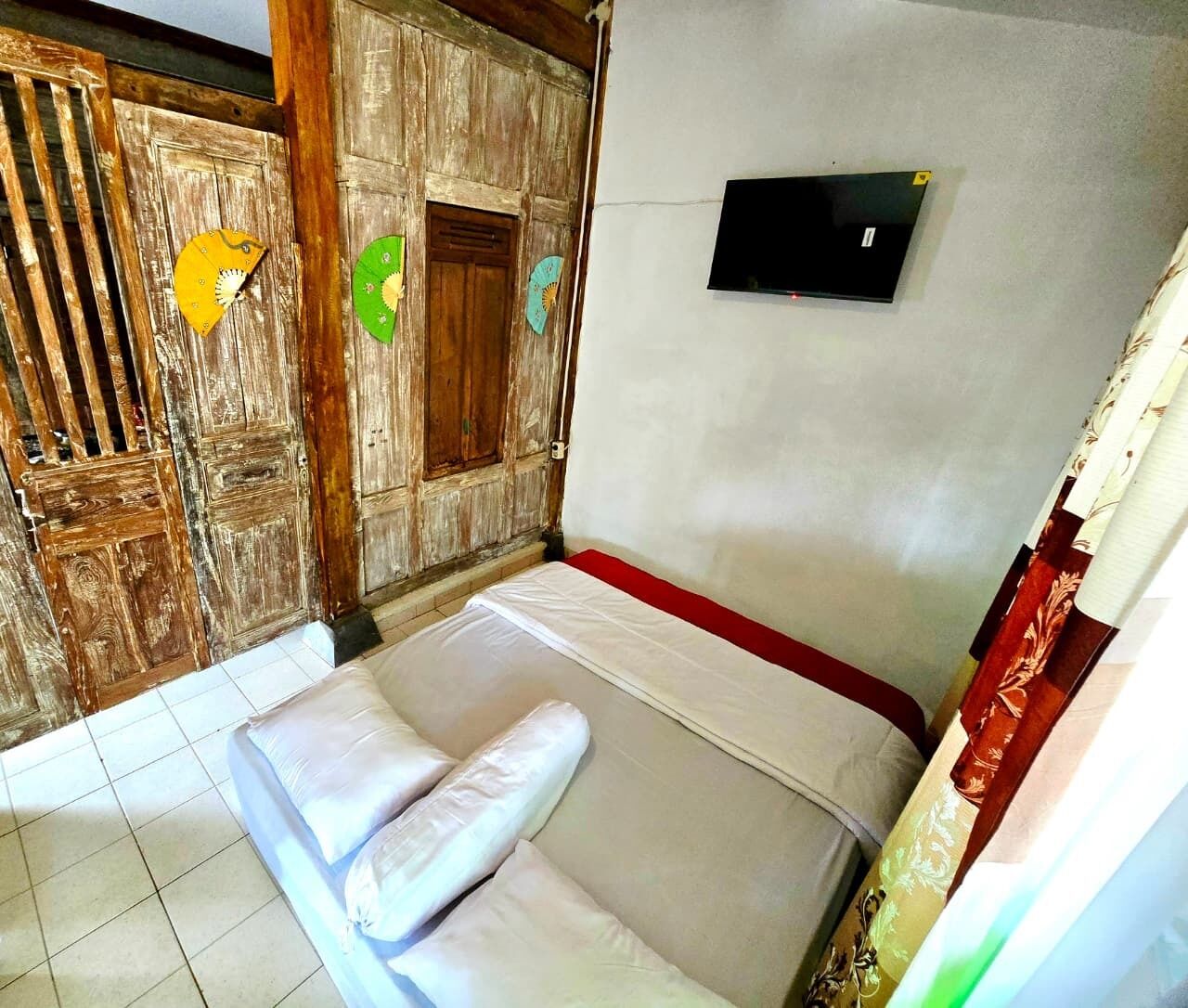 A room with a bed, a wooden door, and a wall-mounted TV.