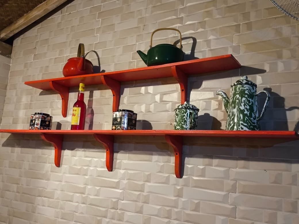 A kitchen shelf with various kitchenware and condiments.