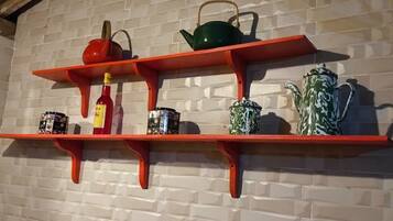 A kitchen shelf with various kitchenware and condiments.