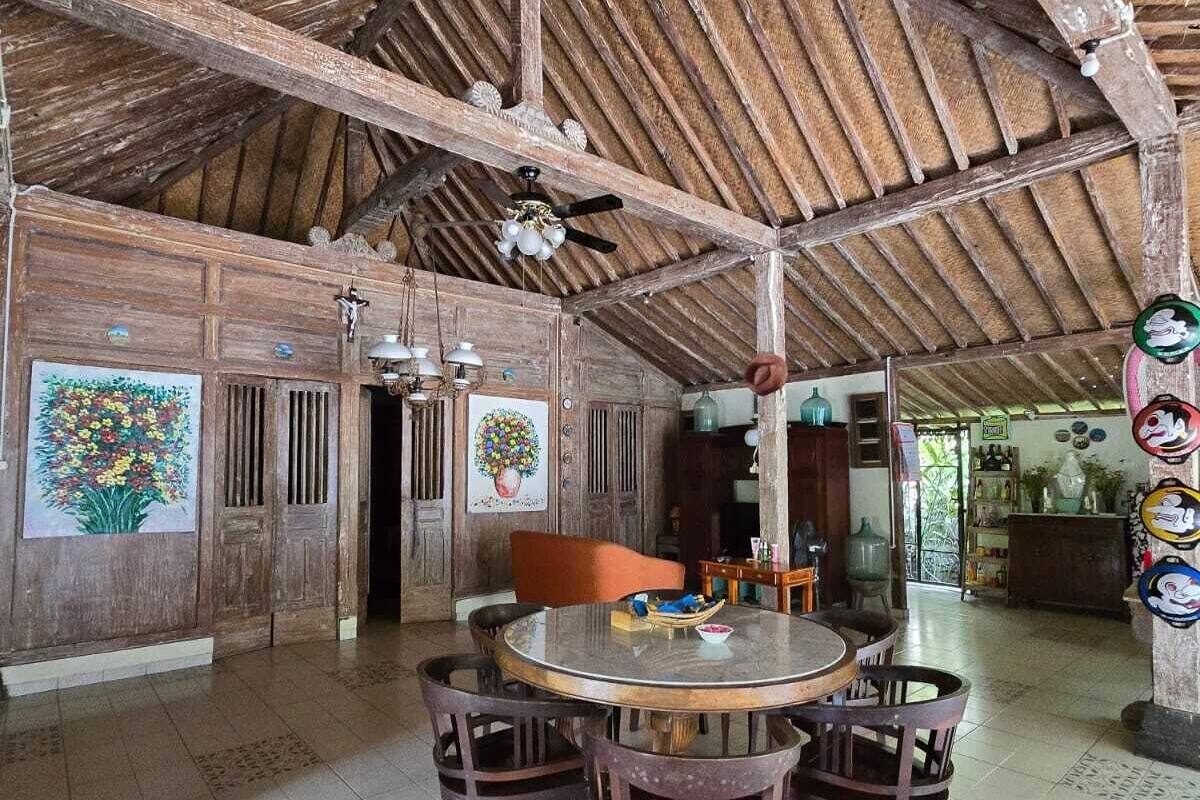 Un interior rústico con un alto techo de madera, una mesa redonda de madera con sillas y baldosas de suelo con diseños.