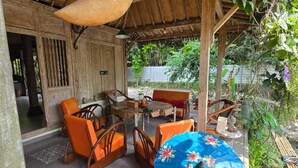 An outdoor seating area with wooden furniture and a blue umbrella. - Eyang Residence Limasan Kebon Dalem (Prambanan)