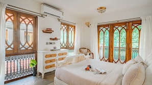 A bedroom with a bed, dresser, and windows with wooden frames.