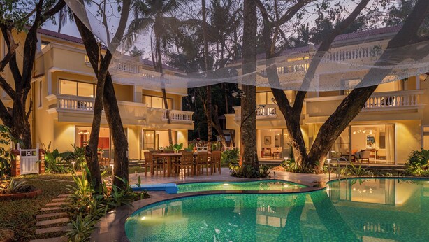 A hotel with a swimming pool, outdoor seating, and a covered patio area.