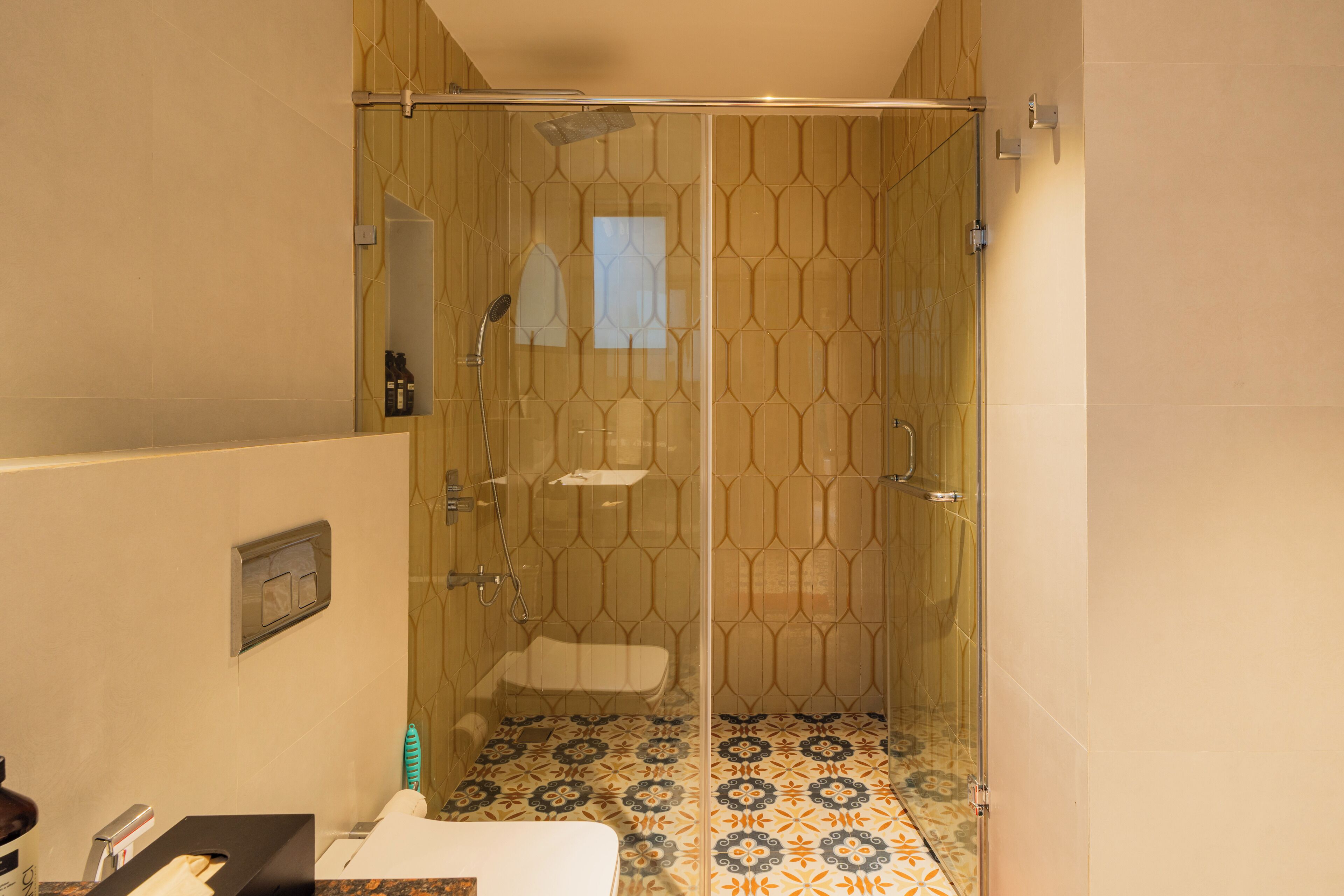 A modern bathroom with a glass-enclosed shower, patterned floor tiles, and a visible toilet.