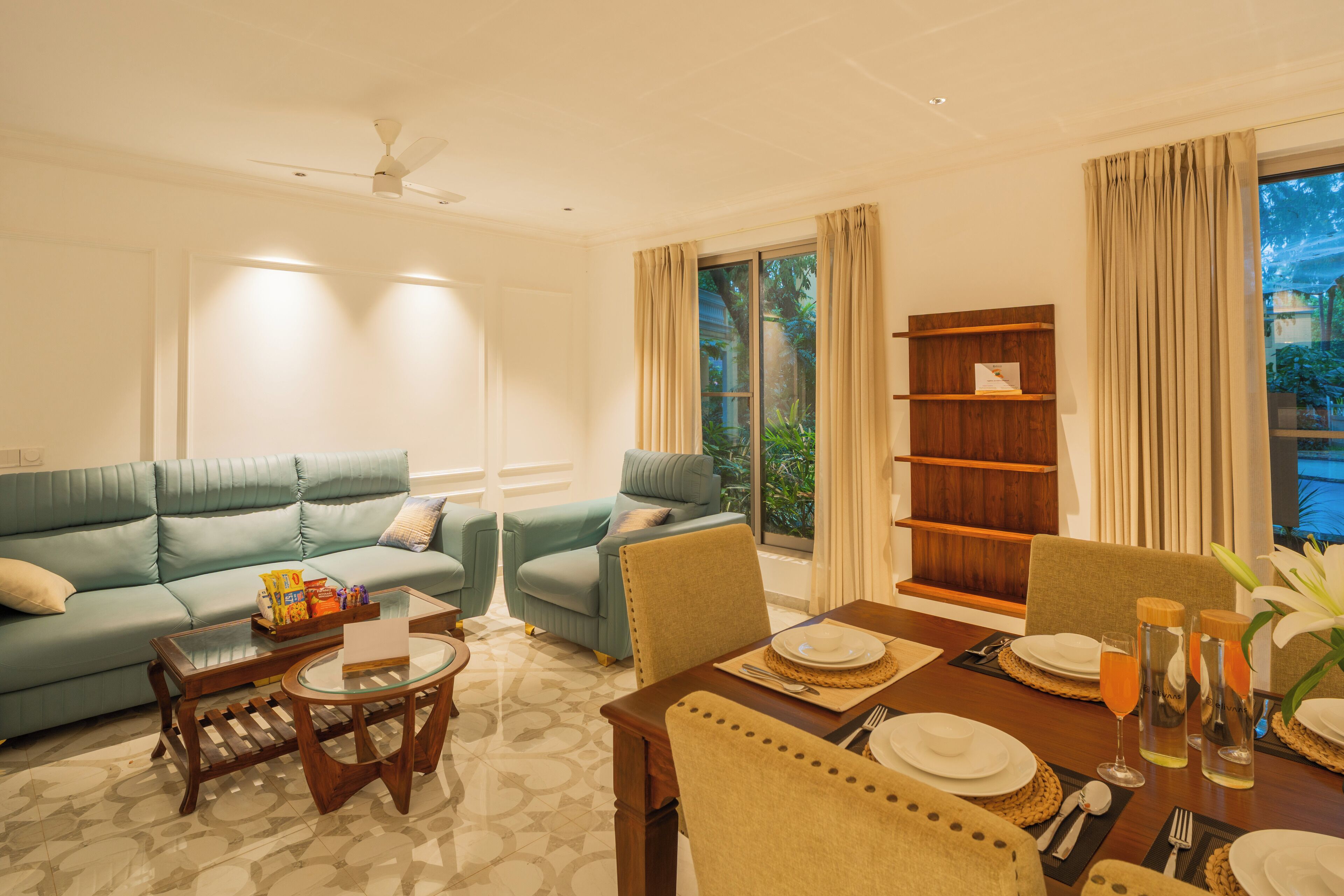 A living room with a sofa, a dining table set for two, and a bookshelf.