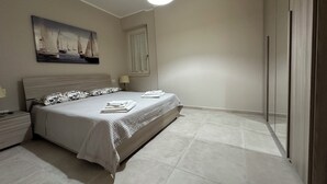 A bedroom with a bed, a nightstand, a lamp, and a painting on the wall. - Casa vacanze La Perla. Alghero, Lido Mari Pia area (Alghero)