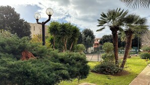 A well-maintained garden with various trees, a basketball court, and a street lamp. - Casa vacanze La Perla. Alghero, Lido Mari Pia area (Alghero)