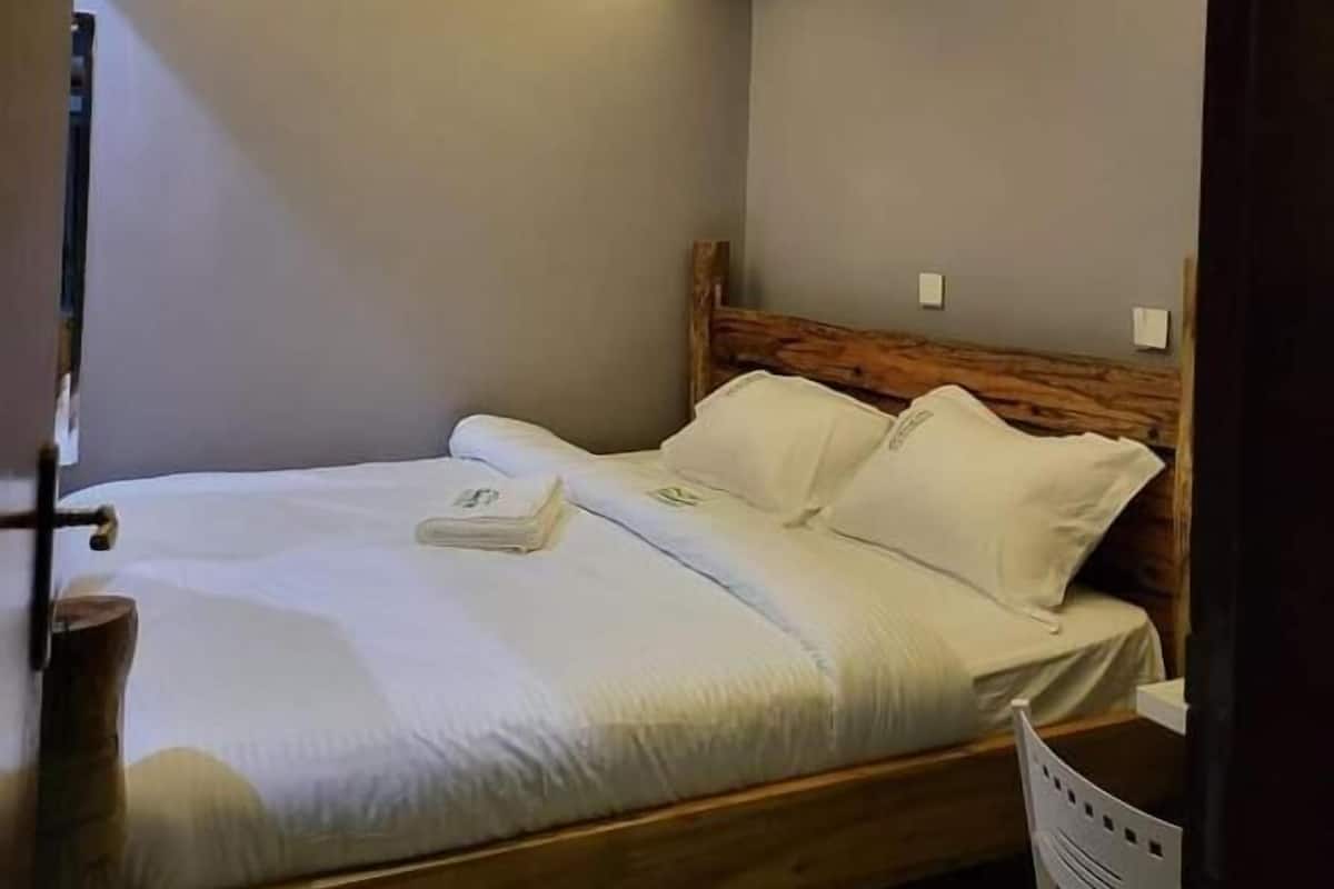 Quarto com cabeceira de madeira, cama com roupa de cama branca e design de teto moderno com luminárias circulares.