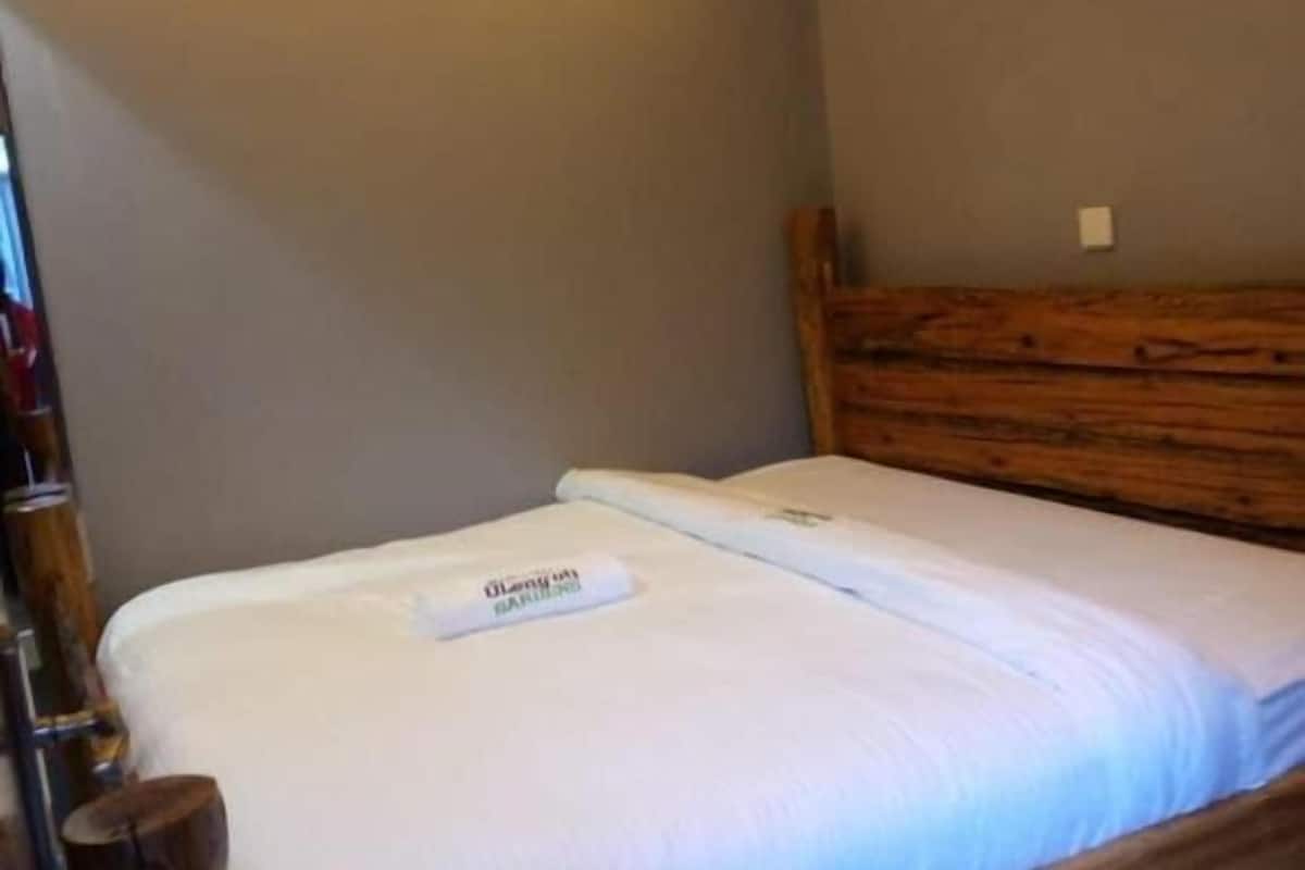 Cama bem arrumada com cabeceira de madeira em um quarto de design simples e clean.