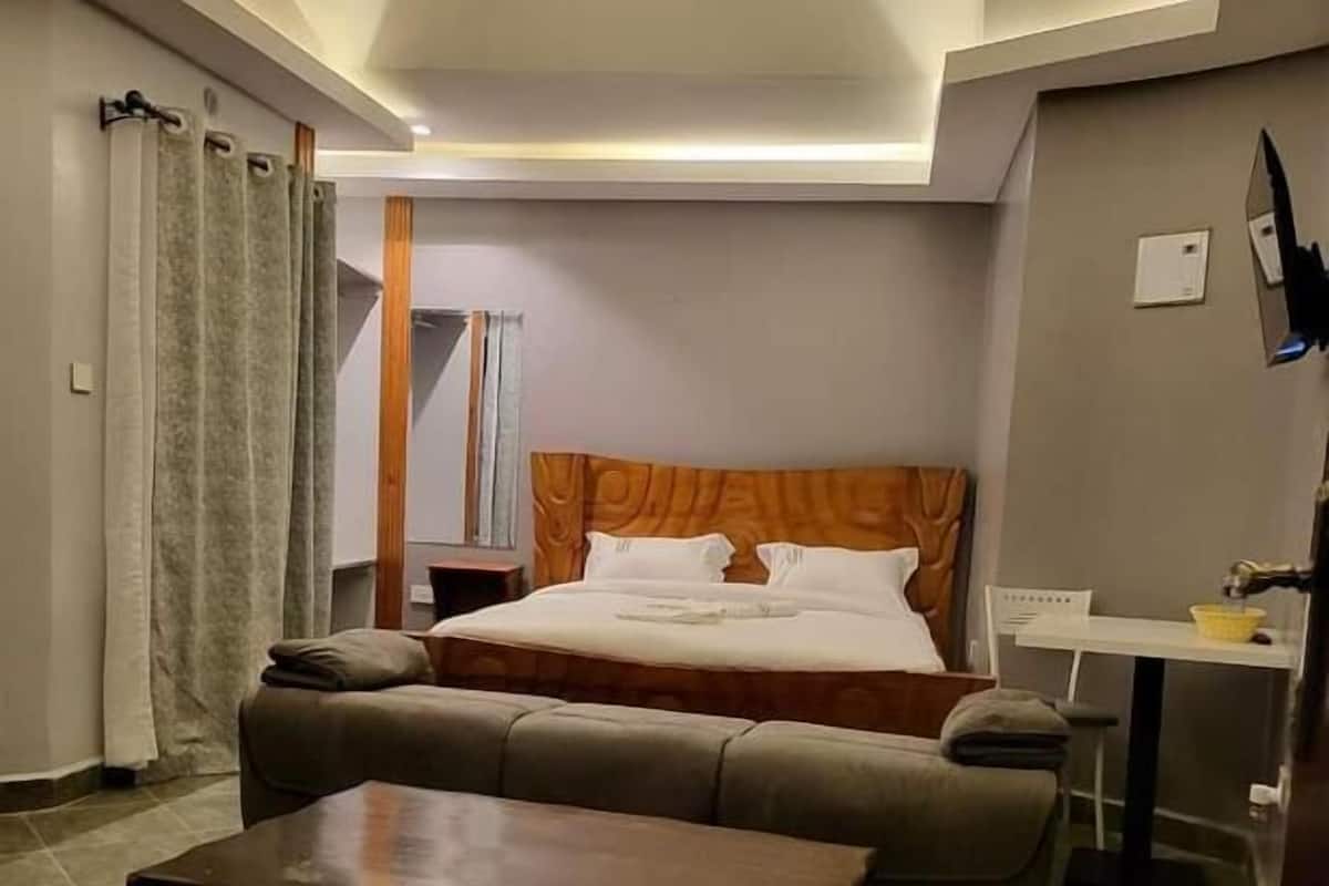 Quarto de hotel com cama, sofá, mesinha e escrivaninha.