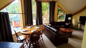 A dining area with a table set for four, a sofa, and a ceiling fan.