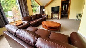 A living room with a brown leather sofa, a wooden coffee table, and a television.