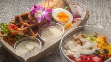 Un repas composé de gaufres, d’un œuf dur et d’une salade, le tout servi dans un récipient en papier.