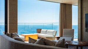 A modern living room with a view of the ocean, furnished with a sofa, armchair, and coffee table. - UMITO ATAMI BETTEI (Atami)