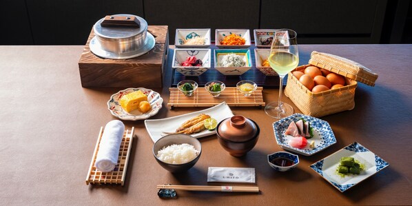 Une variété de plats et d’ustensiles japonais sont disposés sur une table, notamment des sushis, du riz et une théière.