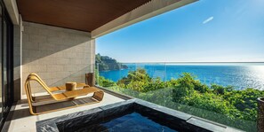 Un balcon avec vue sur la mer, un jacuzzi et des meubles en osier.