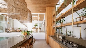 A modern kitchen with a long island, wooden bar stools, and a built-in stove.