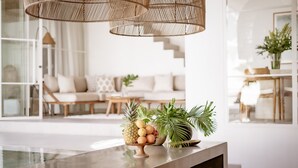 A modern living room with a wooden bench, a sofa, and a dining area with a table.