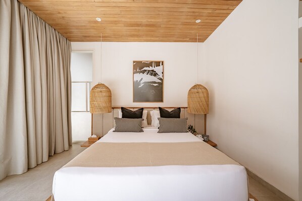 A hotel room with a large bed, wooden ceiling, and a framed picture on the wall.