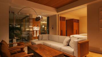 Una sala moderna con un sofá modular, una mesa de centro de madera y un separador de vidrio.
