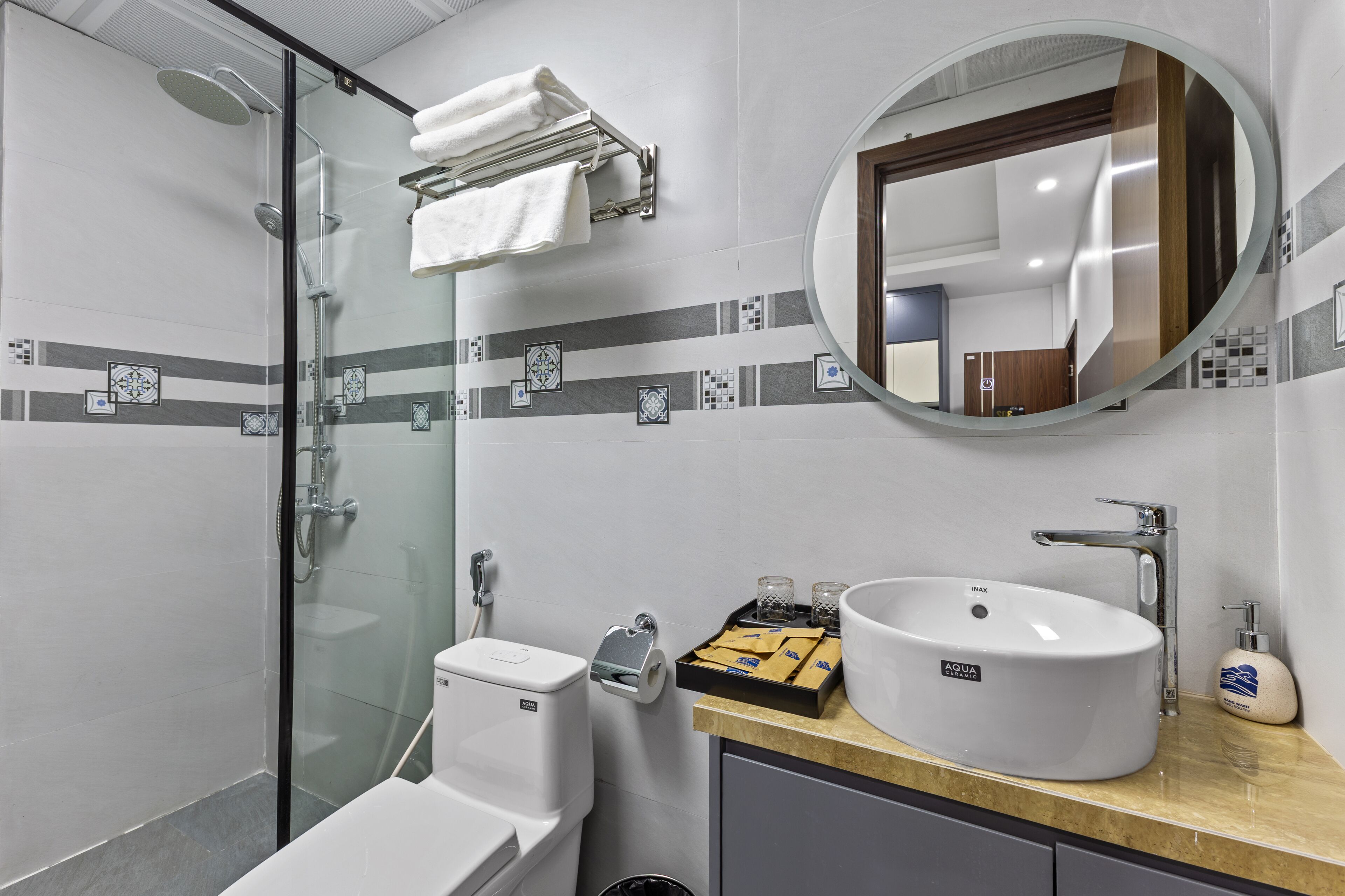A modern bathroom with a glass-enclosed shower, a white sink, and a vanity with a mirror.