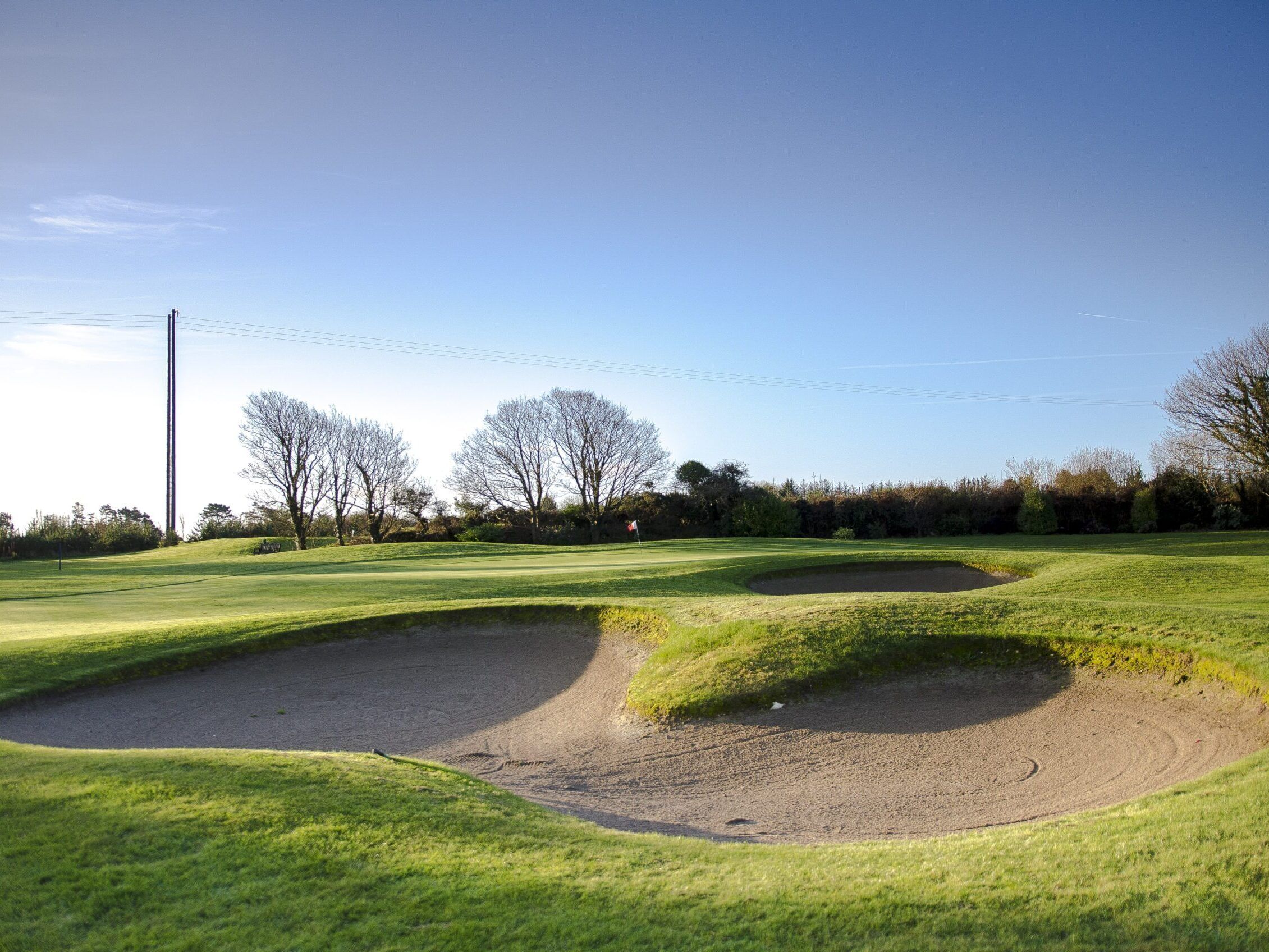Un campo de golf con búnkeres de arena y árboles.
