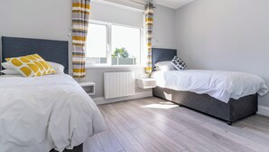 Un dormitorio moderno con dos camas, una ventana con cortinas, un radiador y vistas al exterior.