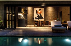 A modern outdoor pool area with a dining setup and a lounge chair.