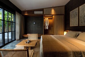A modern hotel room with a large window, a bed, a seating area, and a wardrobe.